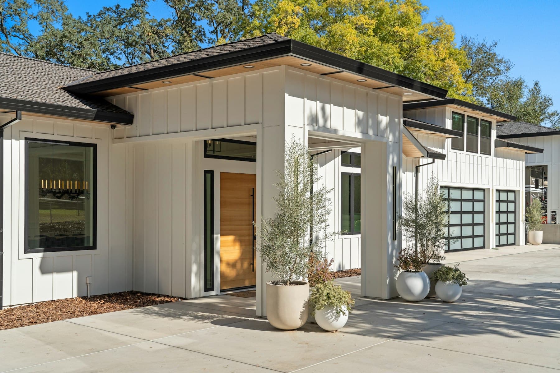 Modern white farmhouse with black-framed glass garage doors