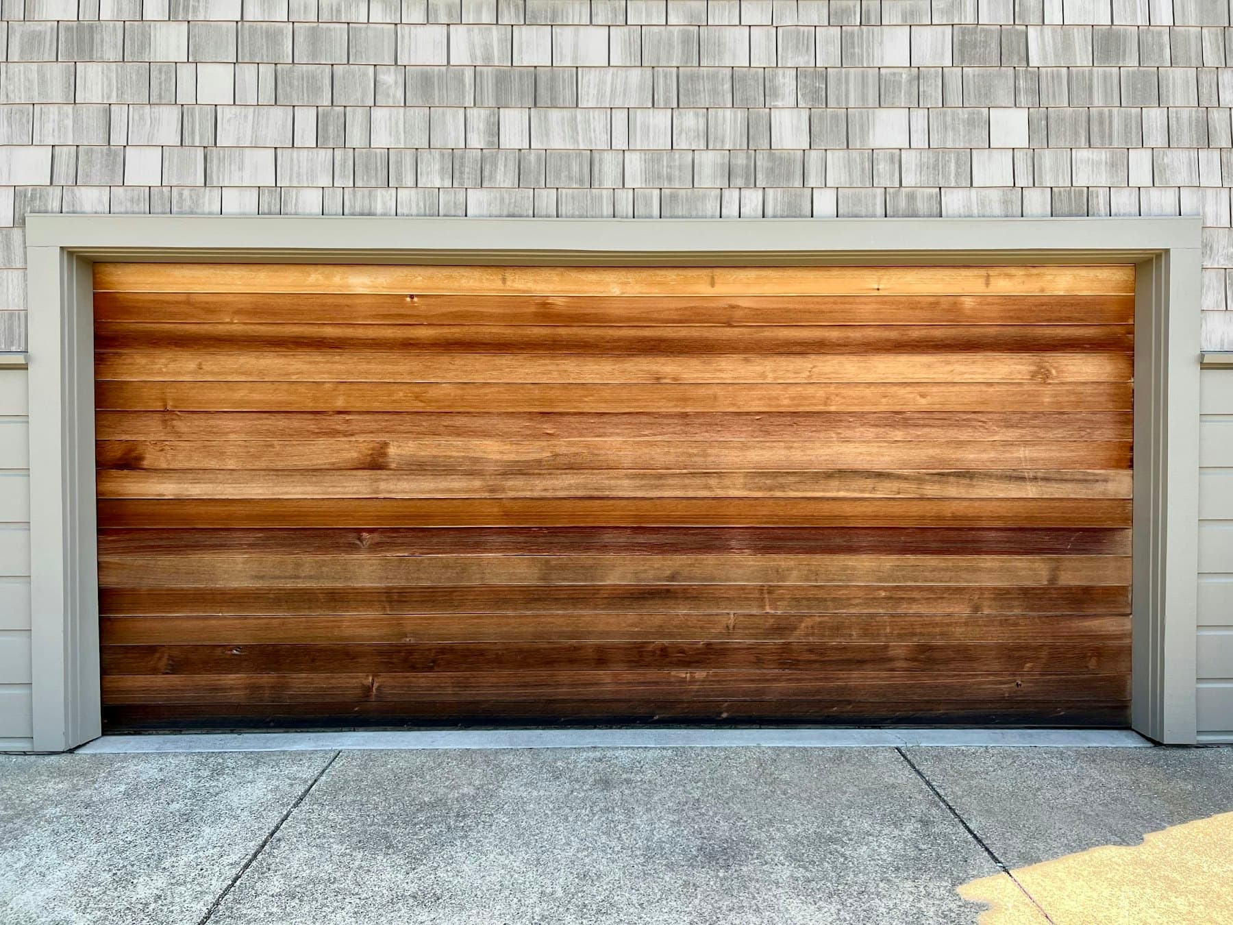 Horizontal cedar plank garage door on a shingle-sided home