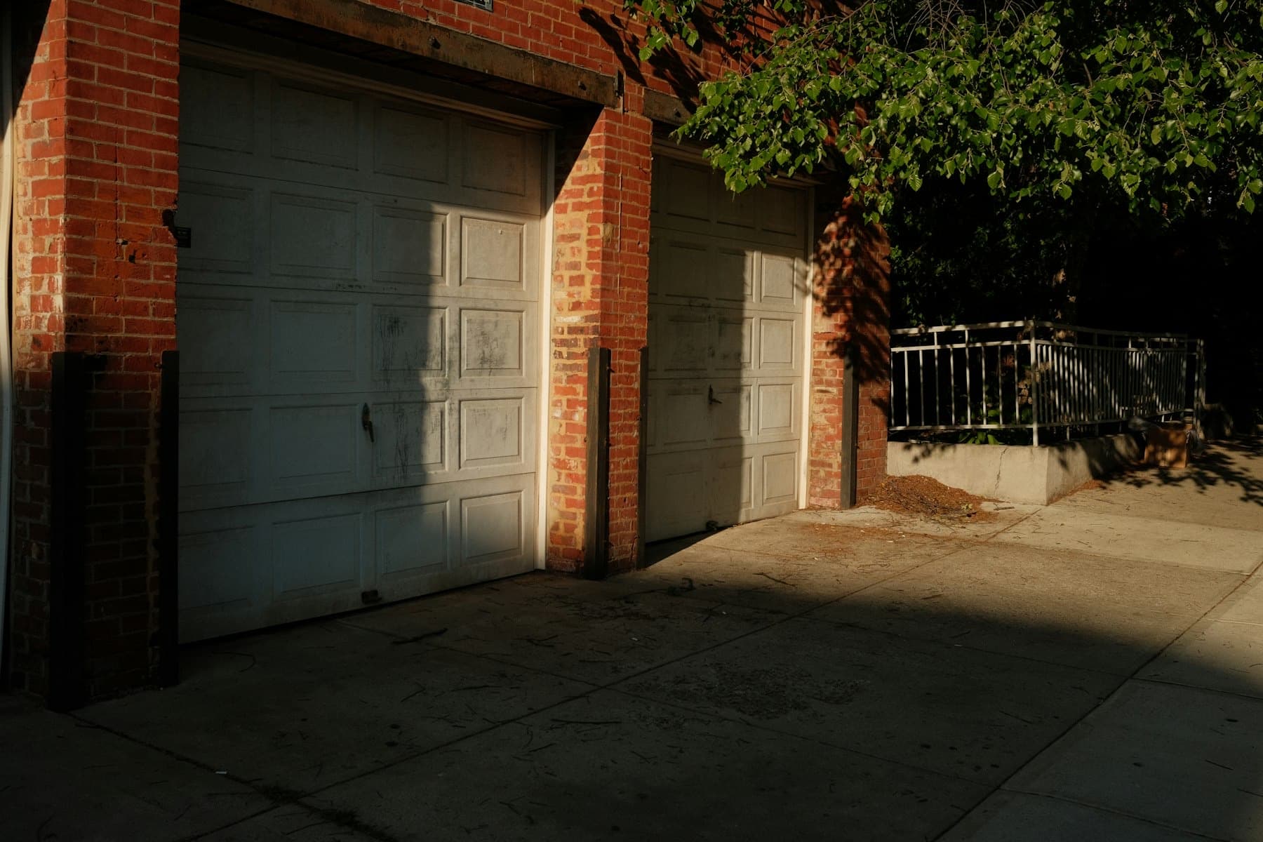 Two white raised-panel garage doors in a brick garage